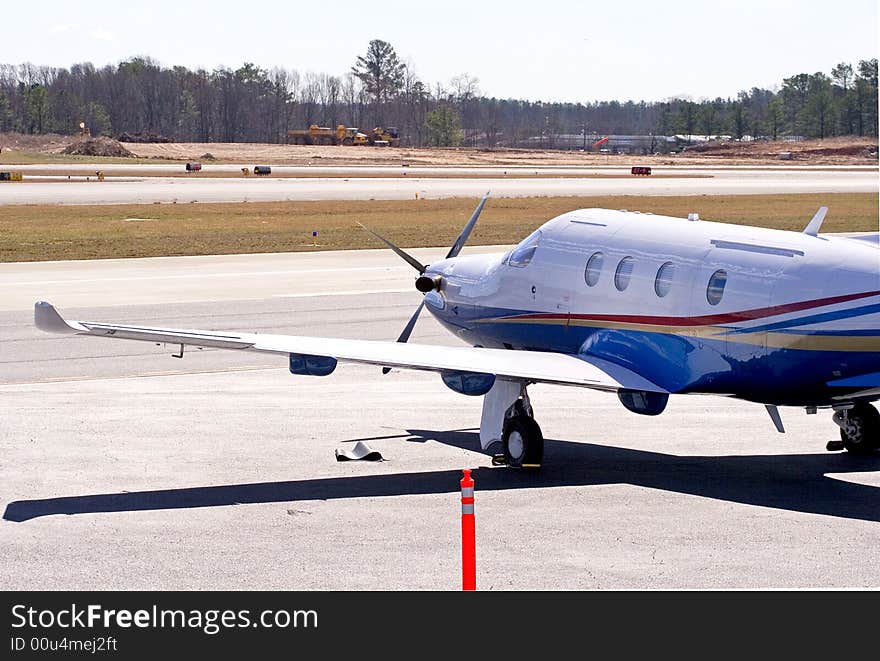 A red, yellow, and blue propeller driven plane on the tarmac at an airport. A red, yellow, and blue propeller driven plane on the tarmac at an airport