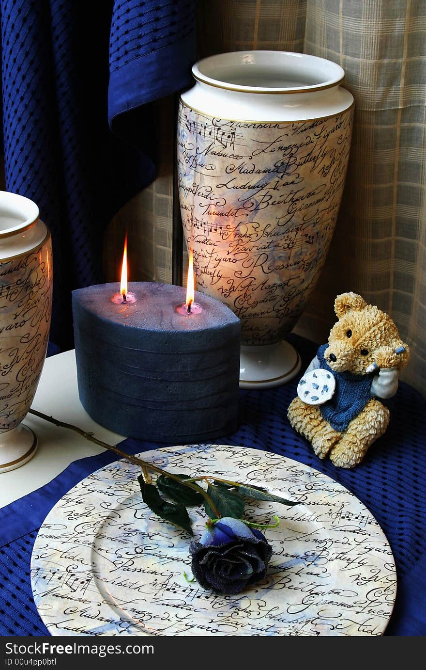 Decorative still-life with a candle, rose and bear in blue. Decorative still-life with a candle, rose and bear in blue.