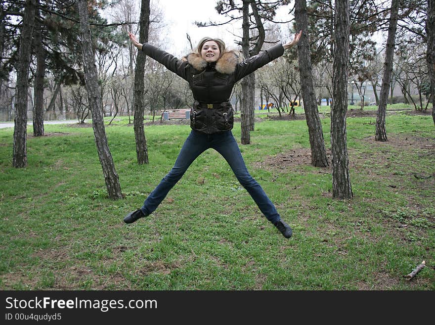 Cheerful smiling girl jump in the meadow