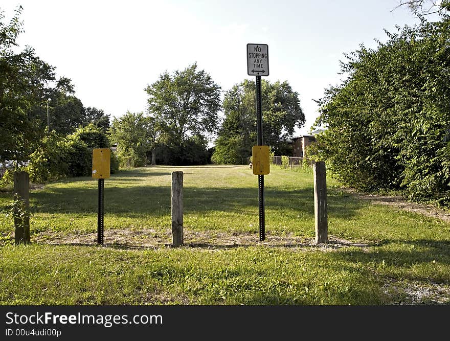 A no parking sign and barriers leading to a park area. A no parking sign and barriers leading to a park area.