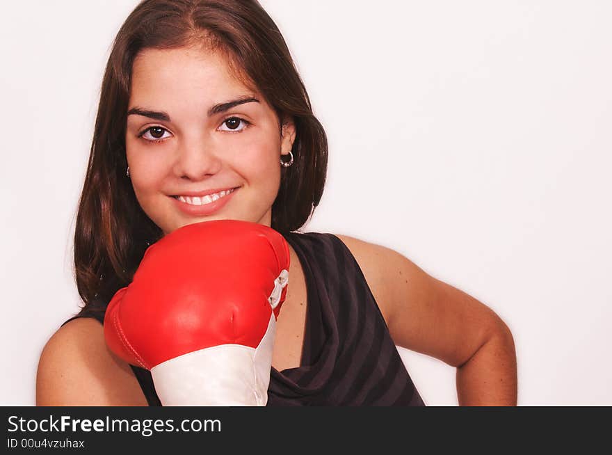 Healthy young woman in red boxing gloves stands smiling with gloves under her chin, her guard up at a cardio boxing workout. Healthy young woman in red boxing gloves stands smiling with gloves under her chin, her guard up at a cardio boxing workout.