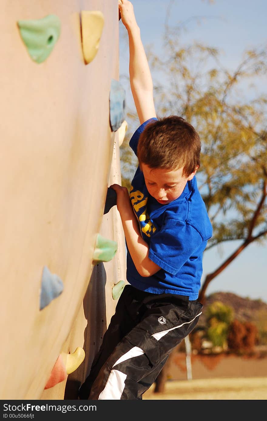 Young boy climbs rock wall at playground. Young boy climbs rock wall at playground.