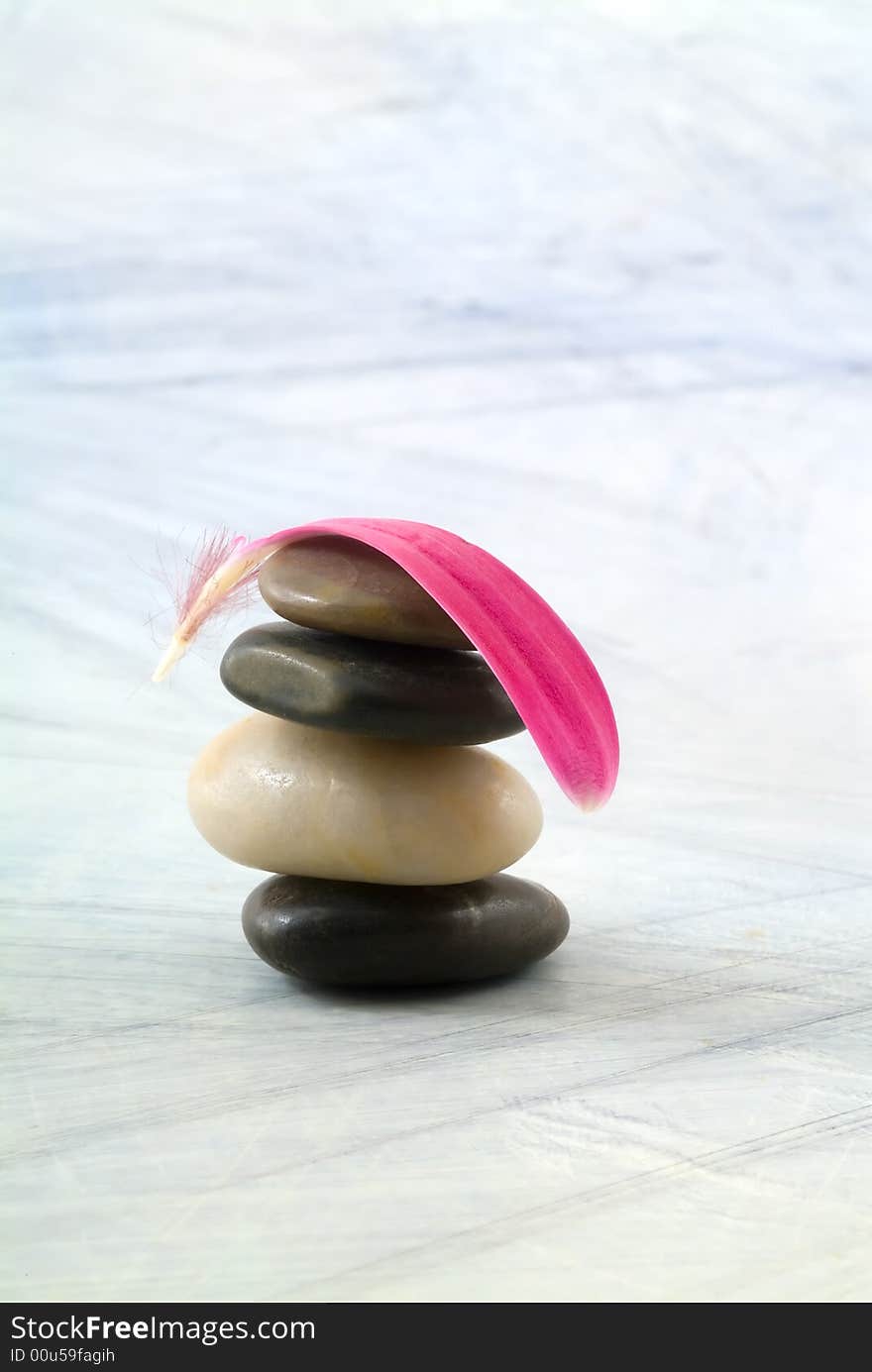 Balancing stones and pink gerber petal on grungy bluish background. Balancing stones and pink gerber petal on grungy bluish background