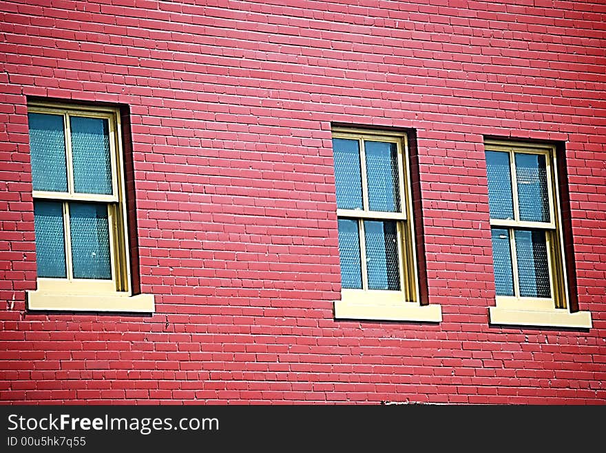 A red brick wall with three windows. A red brick wall with three windows.