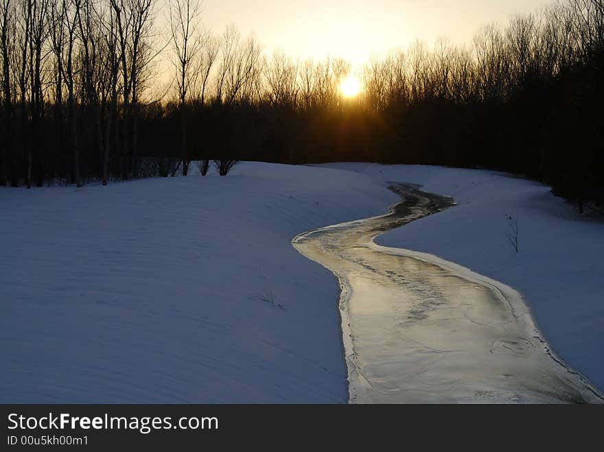 The setting sun lights up a winding creek and reflects off its icy surface. The setting sun lights up a winding creek and reflects off its icy surface