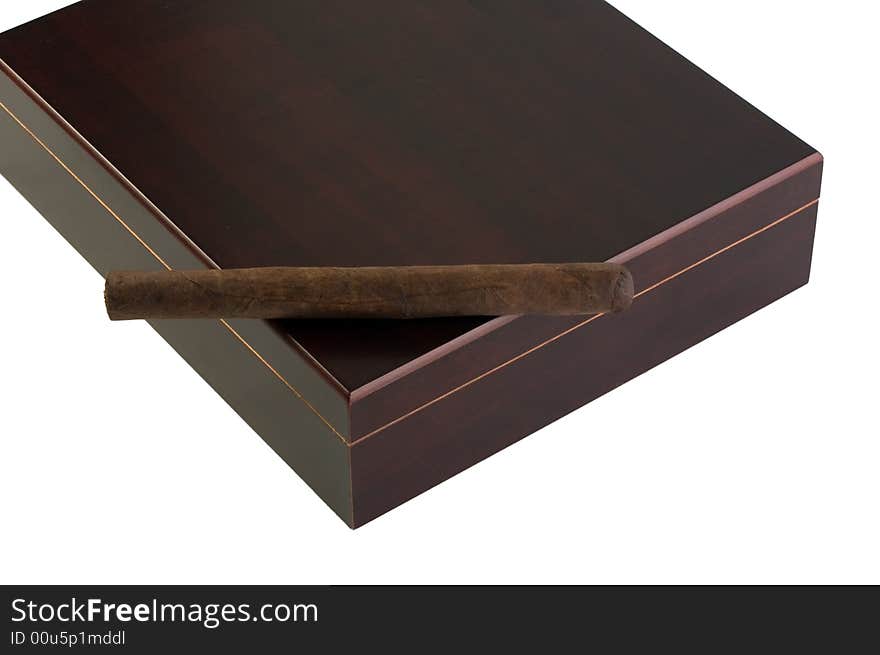 A deep brown Maduro cigar rests atop a dark cherry-wood humidor, with clipping path. A deep brown Maduro cigar rests atop a dark cherry-wood humidor, with clipping path