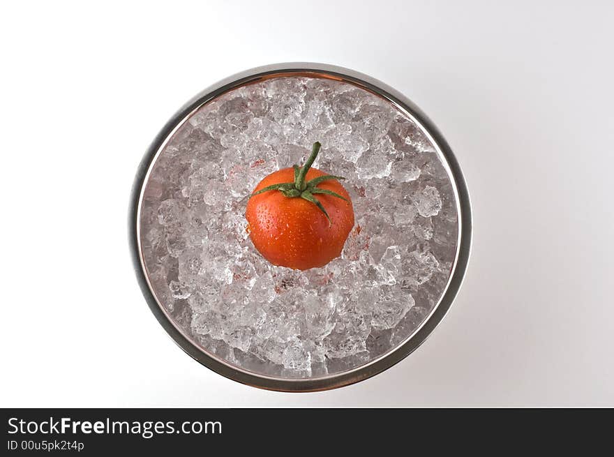 Bright red tomato resting in metal bowl of ice isolated on white. Bright red tomato resting in metal bowl of ice isolated on white