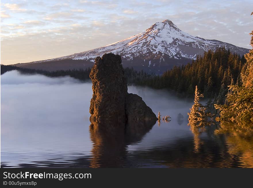 Mountain with simulated flood condition from global warming at sunset with rock coming out of water in foreground at sunset. Mountain with simulated flood condition from global warming at sunset with rock coming out of water in foreground at sunset