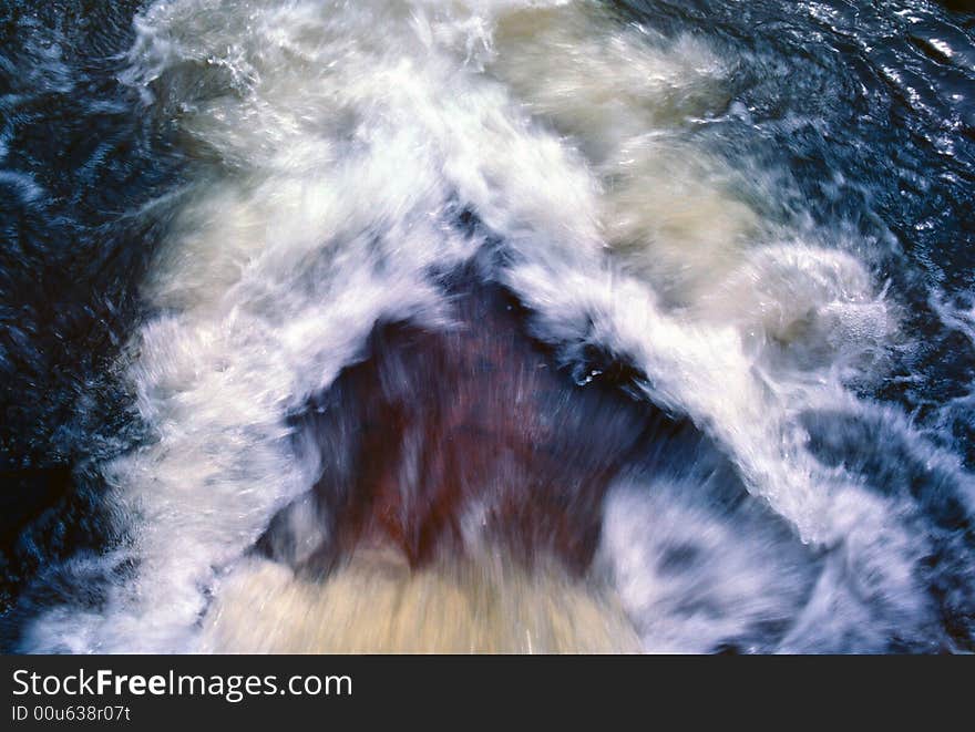 Looking down on a waterfall as it flows into a blue pool of water. Looking down on a waterfall as it flows into a blue pool of water