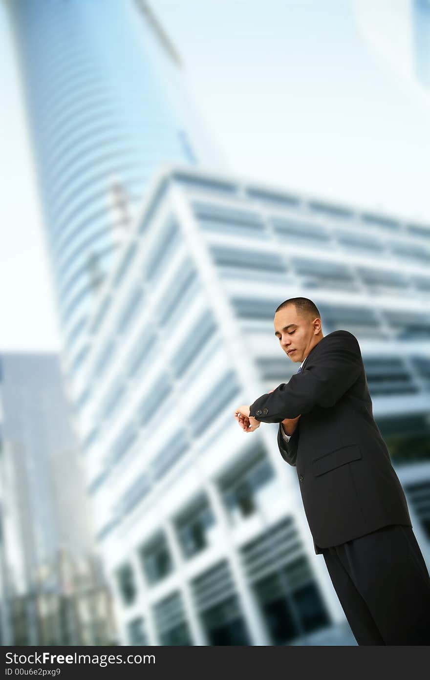 Shot of a man in business suit checking his watch while walking out of his office in downtown area. Shot of a man in business suit checking his watch while walking out of his office in downtown area