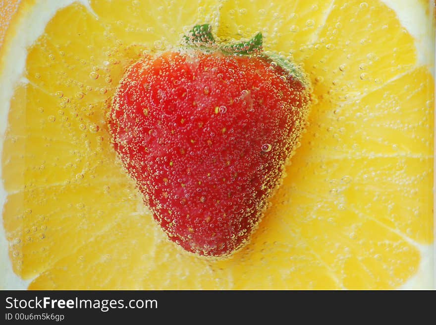 An orange and strawberry in water. An orange and strawberry in water