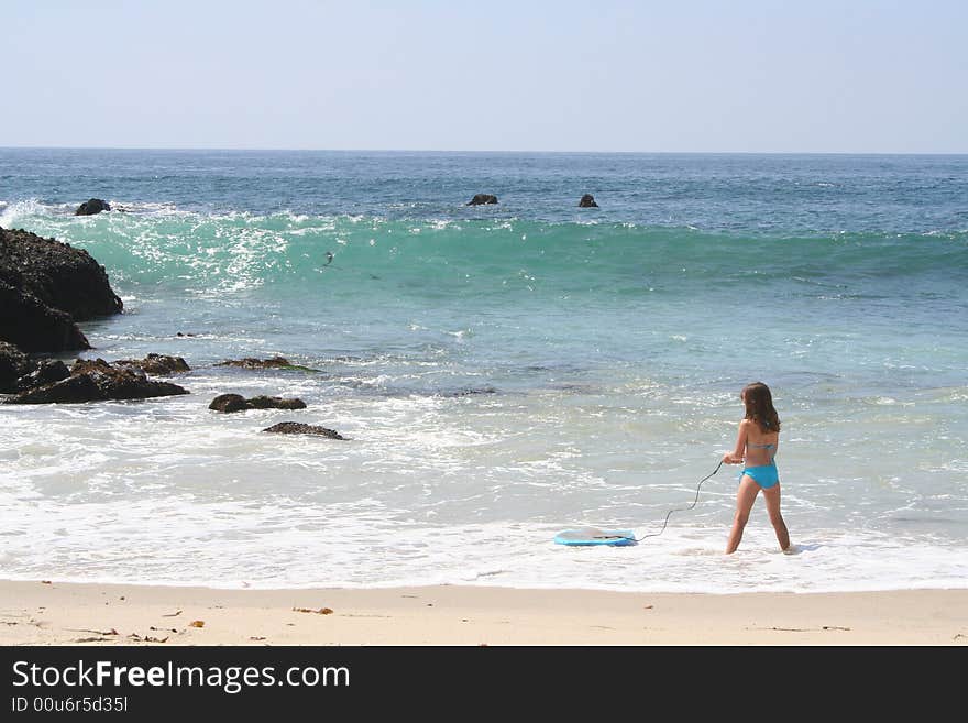 Young girl standing in the water with a boogie board. Young girl standing in the water with a boogie board.