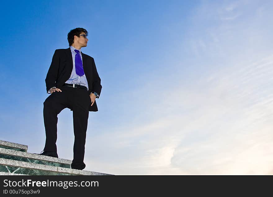 Businessman posing on stairs against blue sky. Businessman posing on stairs against blue sky.