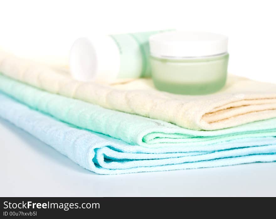 Three towels and cream on a white background. Selective focus. Three towels and cream on a white background. Selective focus.