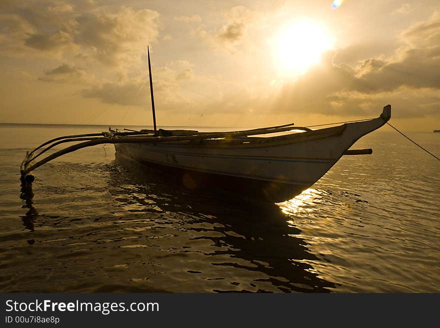 Banca boat at sunset moored on the beach after a busy day. Banca boat at sunset moored on the beach after a busy day