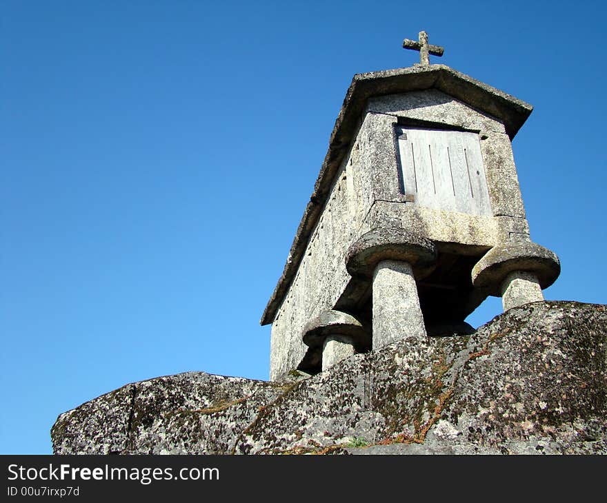 Espigueiro in the sun under blue sky over old stone used to drying corn in Soajo, Portugal. Espigueiro in the sun under blue sky over old stone used to drying corn in Soajo, Portugal