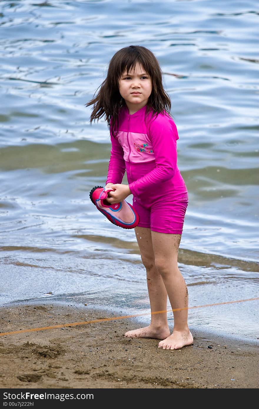 Girl walking on the sand on the beach looking for her shoe. Girl walking on the sand on the beach looking for her shoe