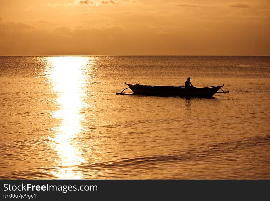 Banca boat sets out to sea at sunset. Banca boat sets out to sea at sunset