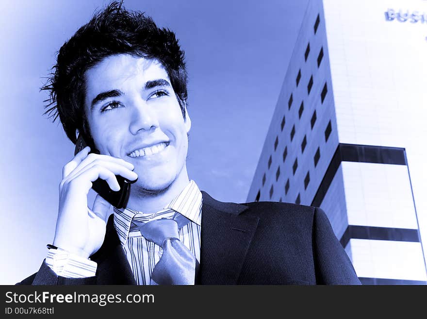 Businessman on phone over urban background, blue toned.