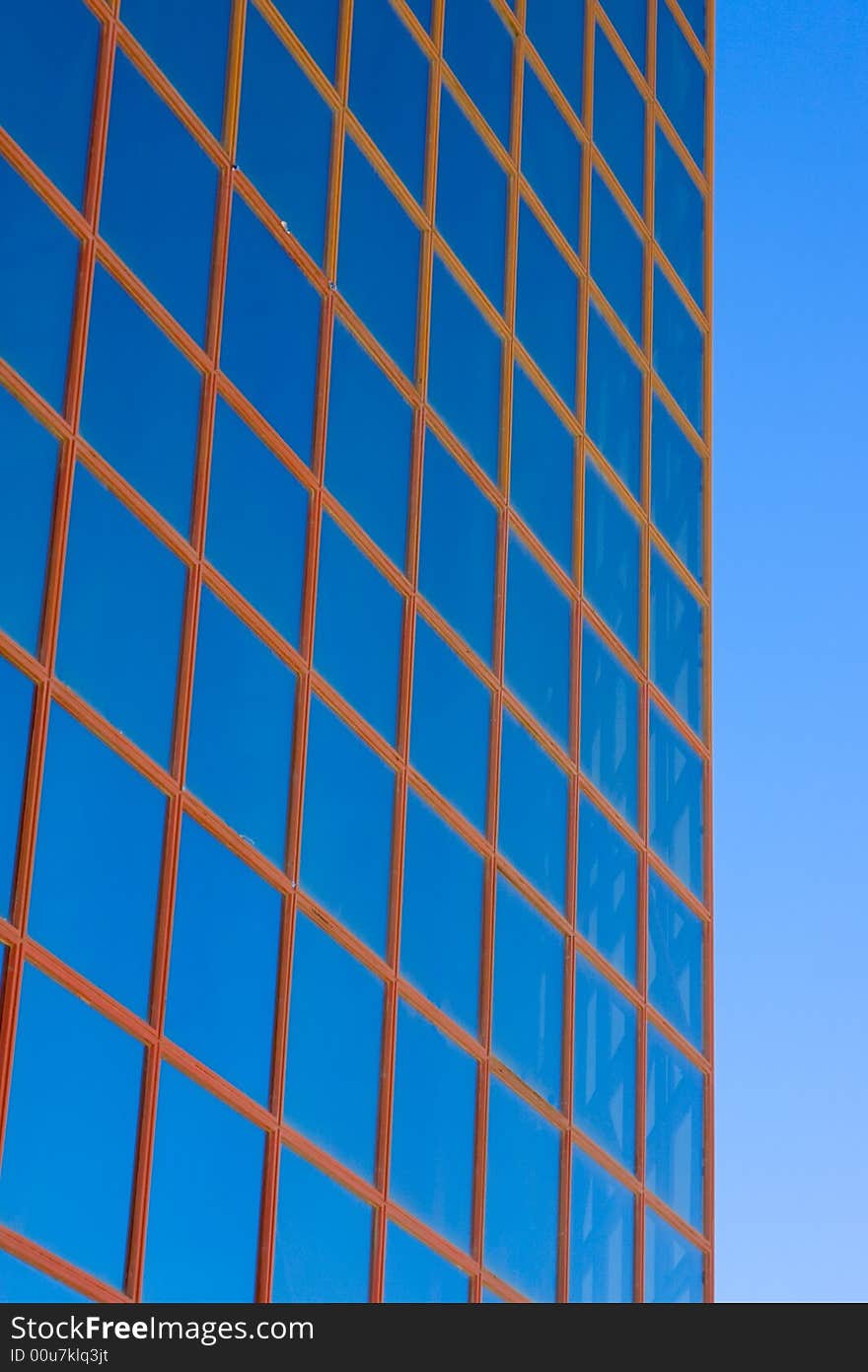 Blue windows from office building against blue sky.