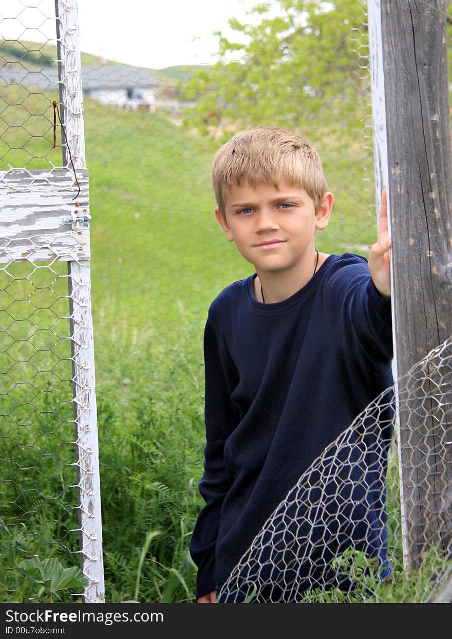Boy standing in outdoor structure on farmland. Boy standing in outdoor structure on farmland.