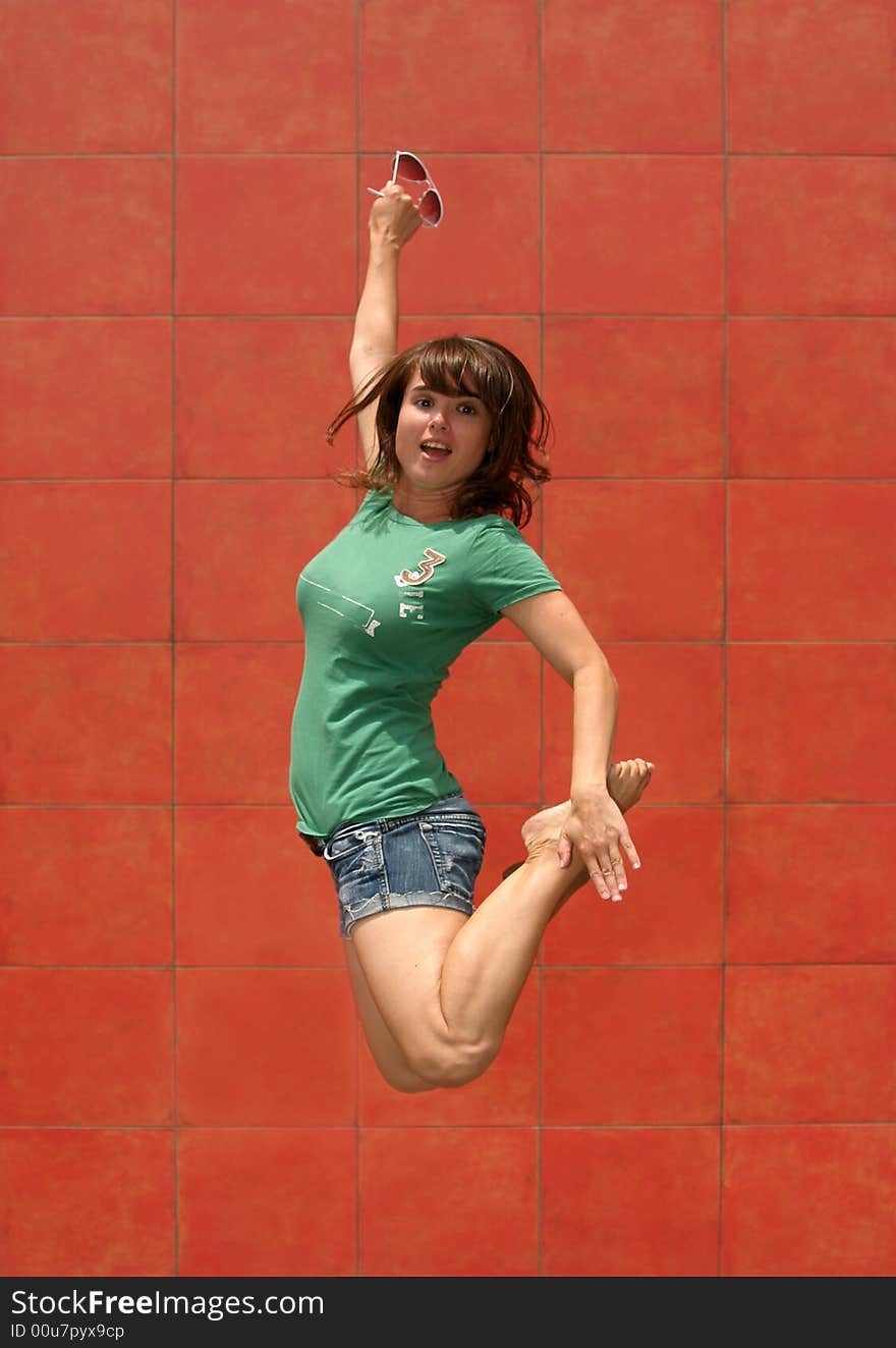 - a model jumps in front of a red wall. - a model jumps in front of a red wall