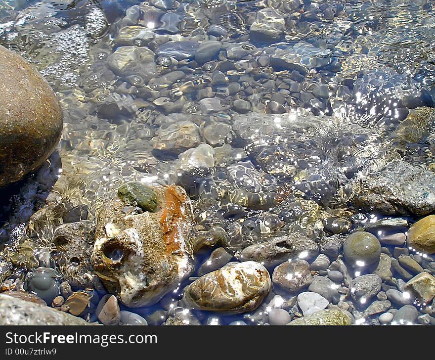 Sea water, pebble. Clear sea water of coast. The stone bottom is visible.