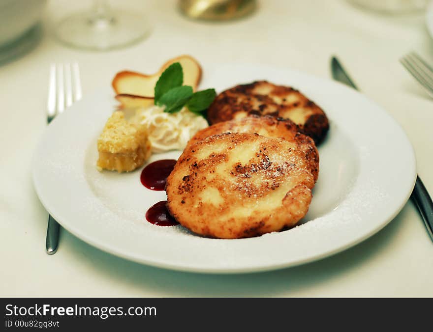 White dish with pancakes, honey and jam on table in fine restaurant. White dish with pancakes, honey and jam on table in fine restaurant