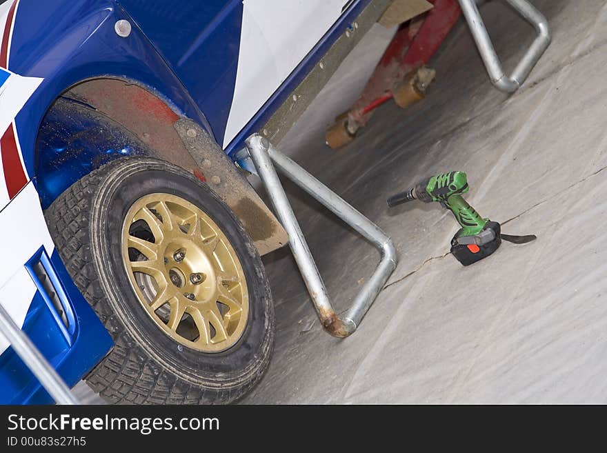 Detail of a rally car wheel and some tools at the pit stop.