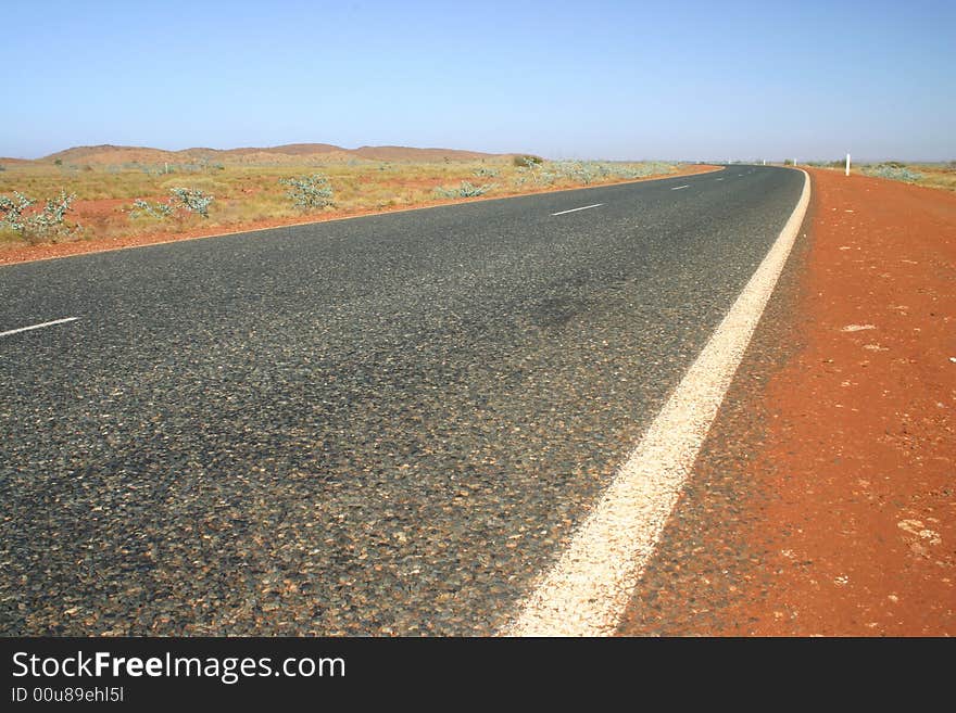 Typical Australian road with red dirt and arid landscape. Australia.