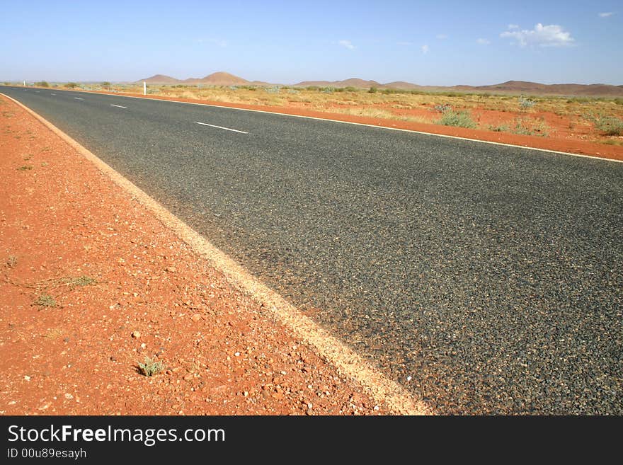 Typical Australian road with red dirt and arid landscape. Australia.