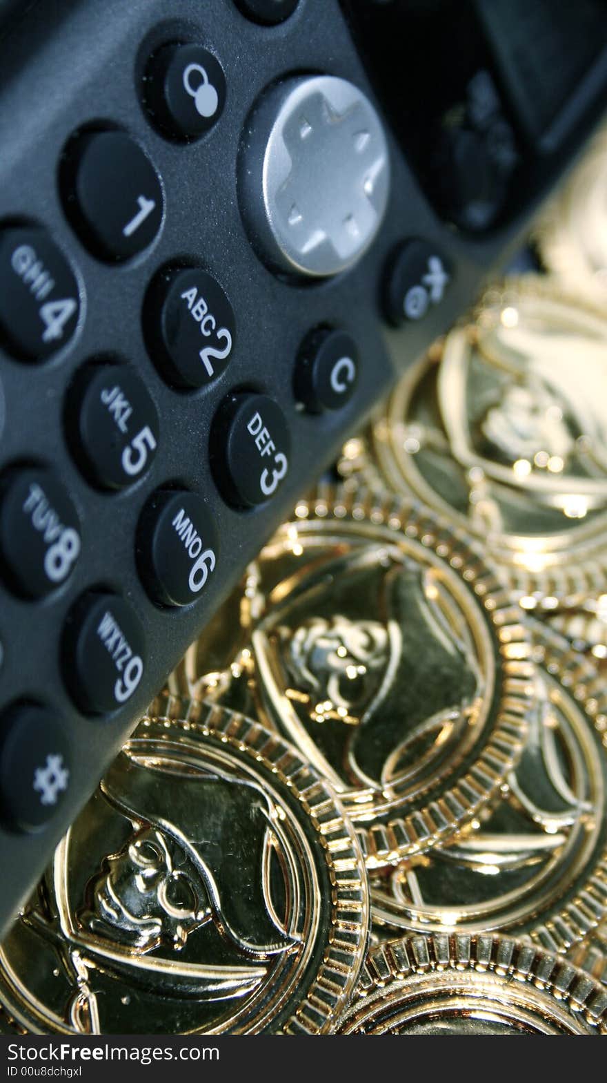 A phone lying next to a pile of golden money with pirates heads printed on them. A phone lying next to a pile of golden money with pirates heads printed on them