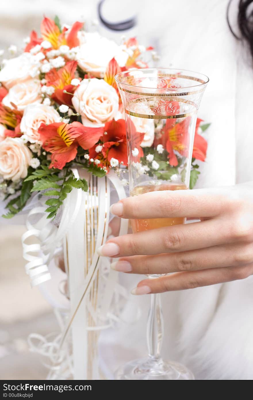 Hand of bride holding glass of champagne. Low DOF, focus on glass. Hand of bride holding glass of champagne. Low DOF, focus on glass