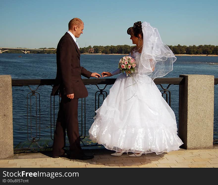 Newly wedded couple walking on near the river