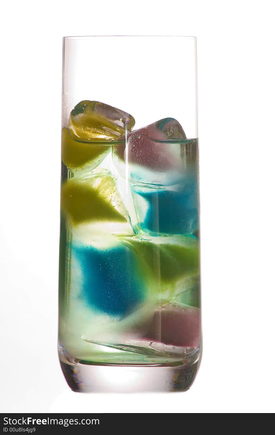 A glass of clear water and colored ice cubes over a white background