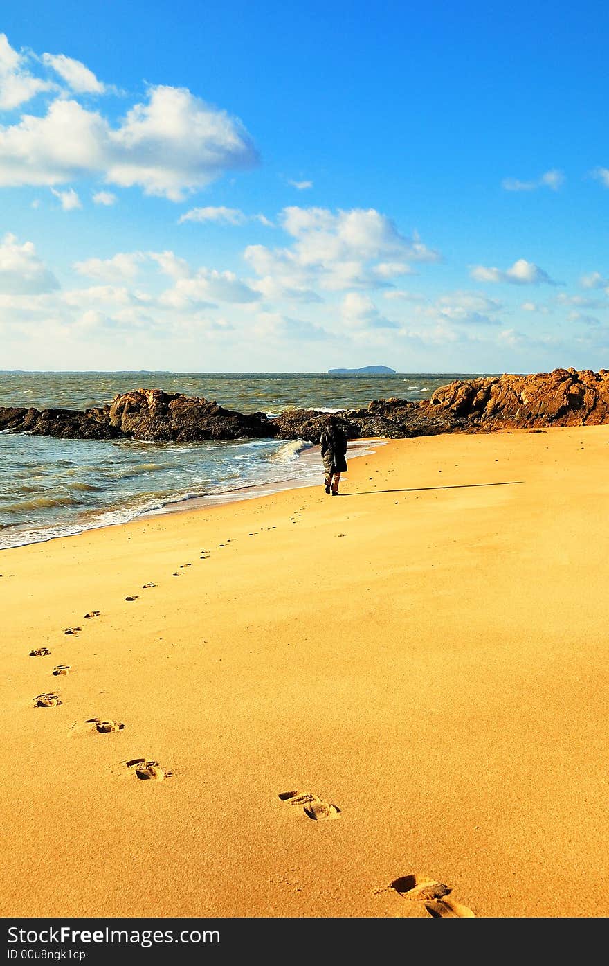 The setting sun of winter , one woman had been visited from the sandy beach , have left a string of footmark.