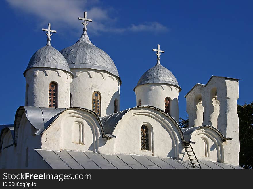 On a photo domes of the church on a background of the blue sky with a cloud. Russia, Pskov, summer day.