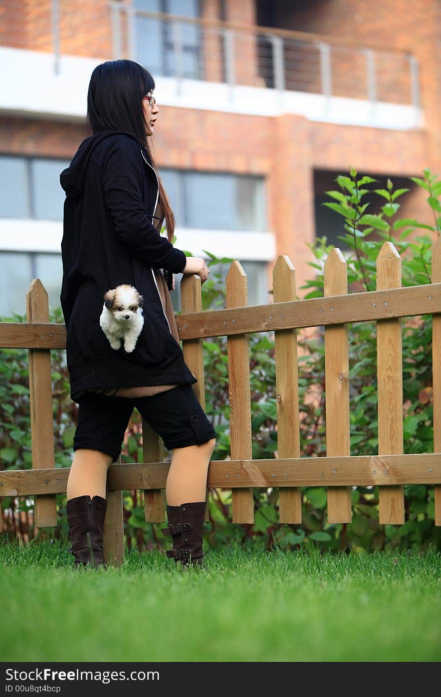 A baby dog in the girl's pocket, they are waiting