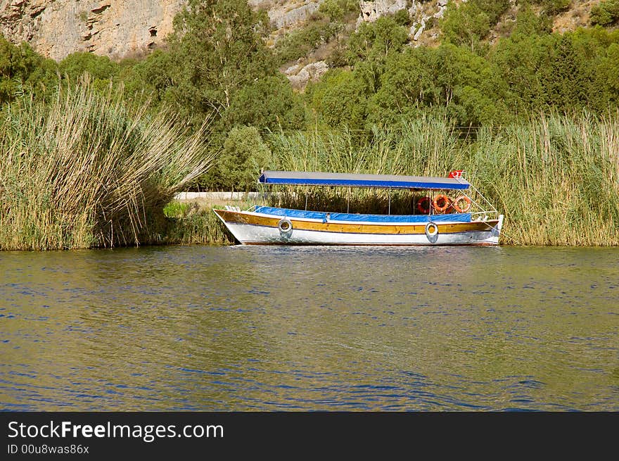 Fishing boat moored near reeds on the river coast