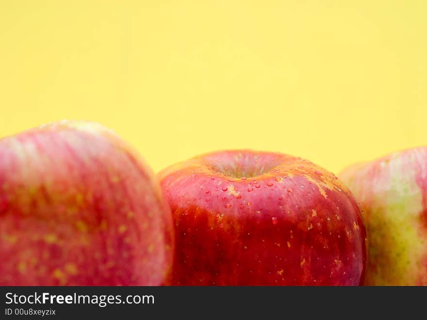 Fresh red apples on a bright yellow background with shallow focus. Fresh red apples on a bright yellow background with shallow focus