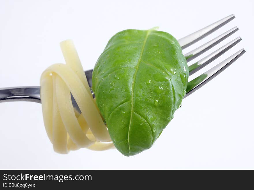 Tagliatelle on a fork with a basil leaf