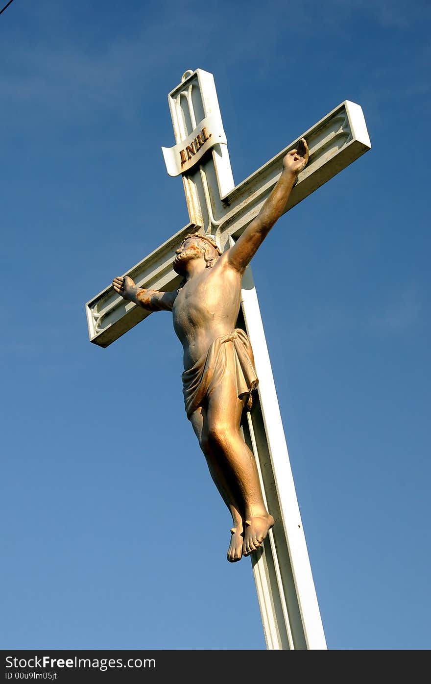 Realistic statue of Christ on the cross against blue sky. Realistic statue of Christ on the cross against blue sky