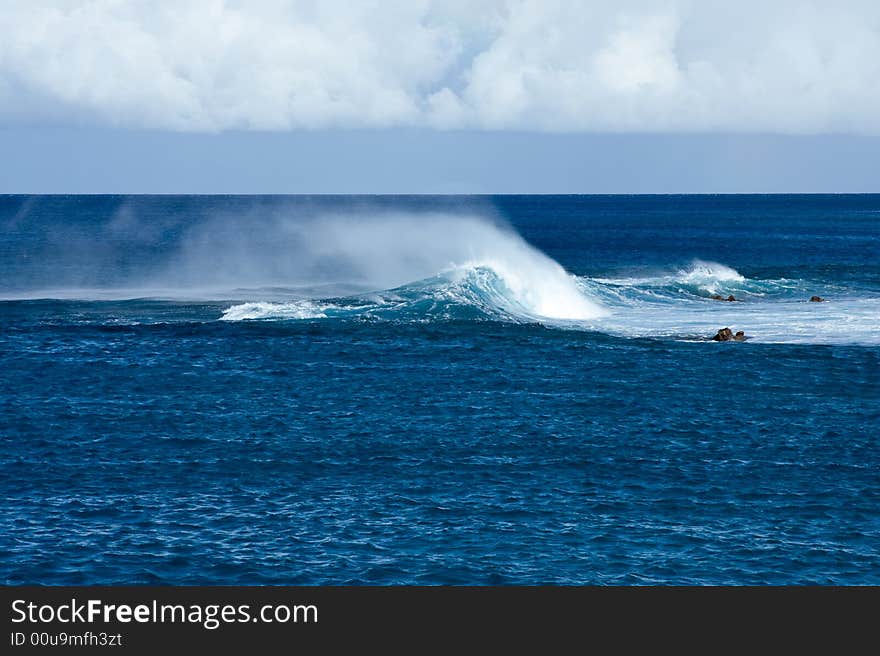 Crashing waves off Hawaii in strong wind resulting in blowing spray. Crashing waves off Hawaii in strong wind resulting in blowing spray