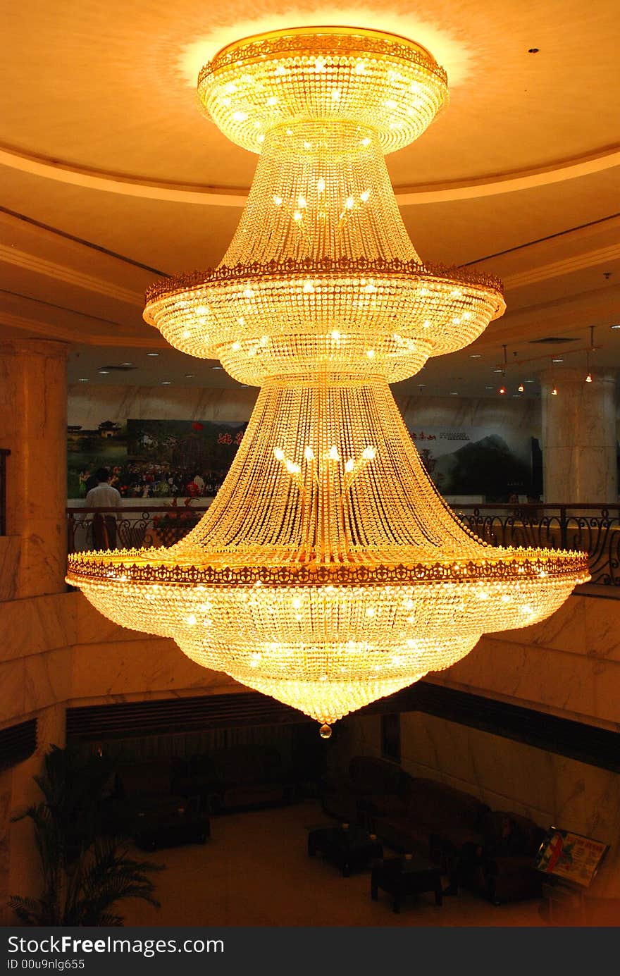 A big golden pendant lamp in a hotel lobby hung from the wood ceiling.