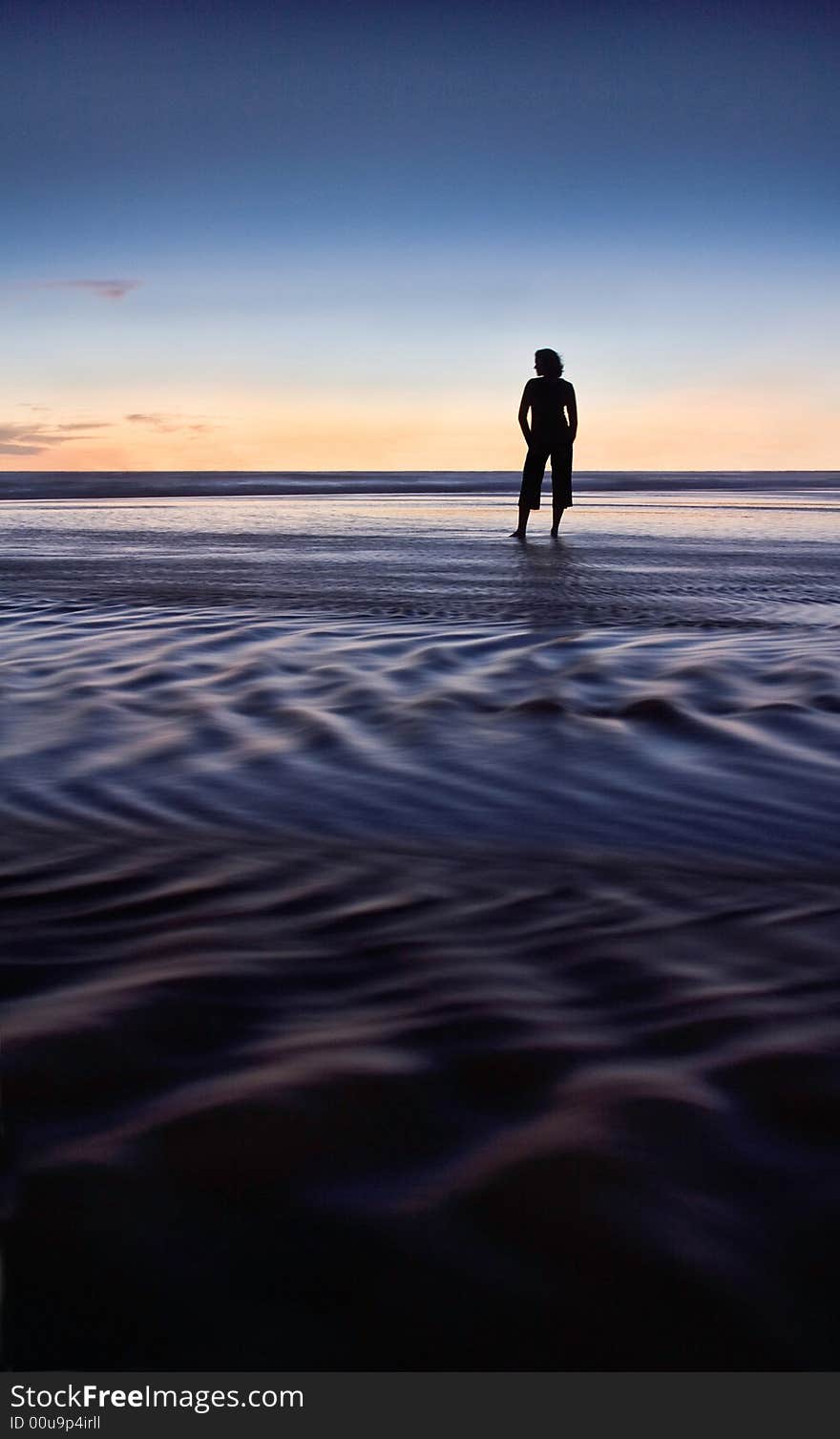 Woman relaxing on the beach , silhouetted against the sunset sky. Woman relaxing on the beach , silhouetted against the sunset sky.