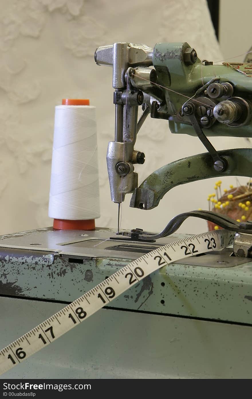 An old fashioned sewing machine with a wedding dress background