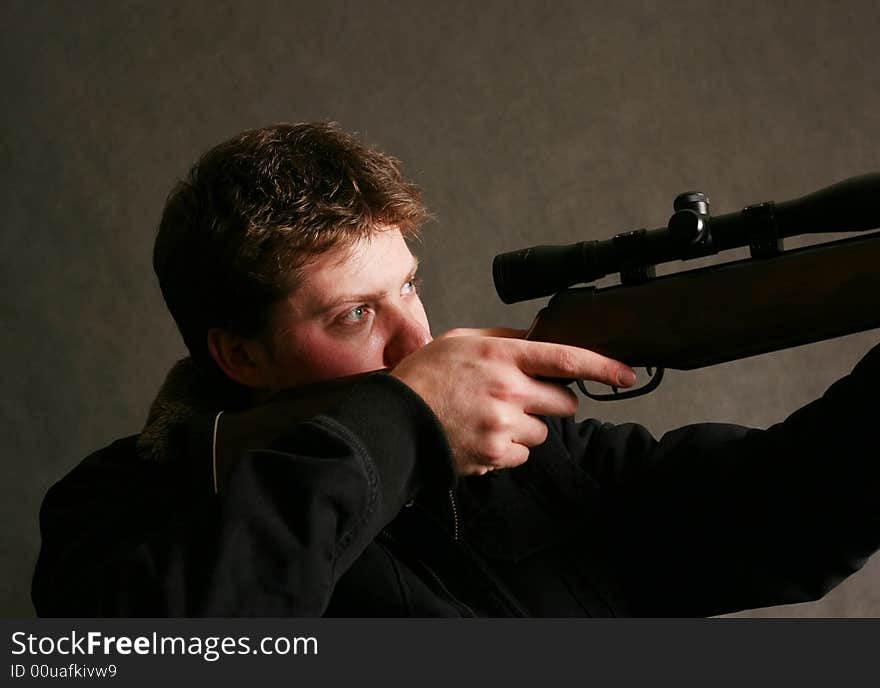 The man with the weapon in studio on a dark background. The man with the weapon in studio on a dark background