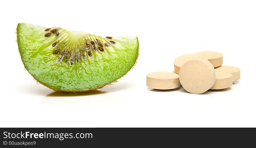 Segment kiwi and a handful of tablets on white. Isolation on white. Shallow DOF. Segment kiwi and a handful of tablets on white. Isolation on white. Shallow DOF.