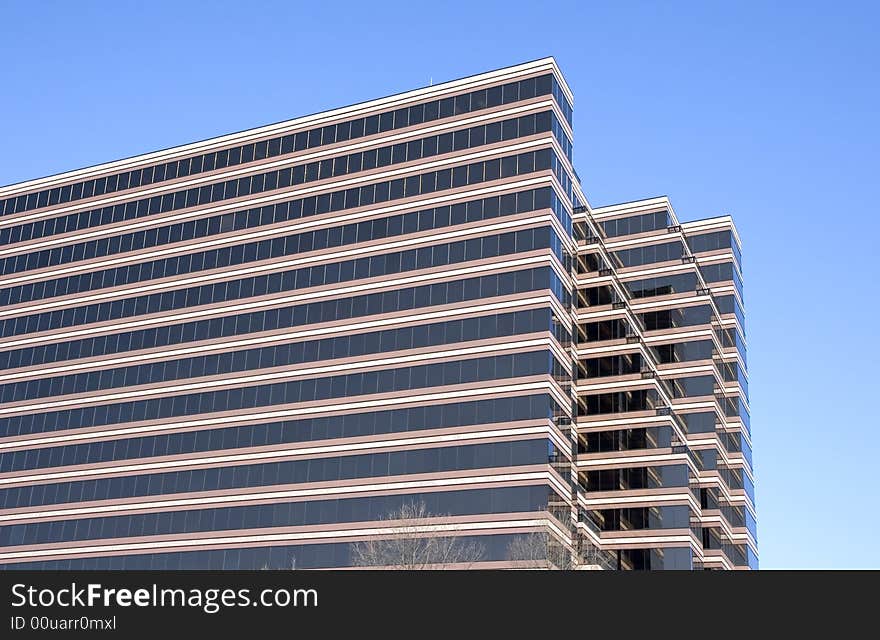 A brown concrete and glass building against a blue sky. A brown concrete and glass building against a blue sky