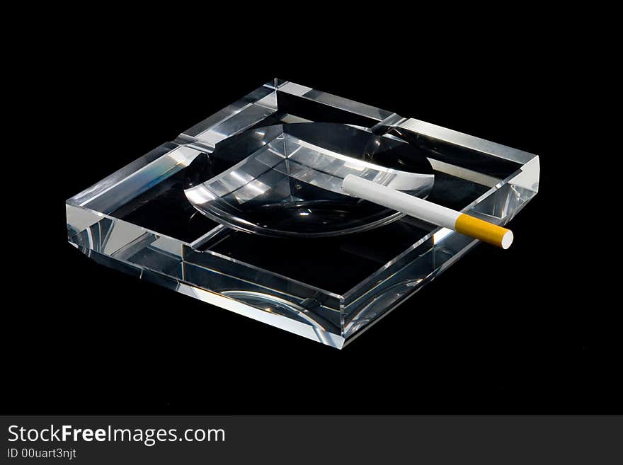 A crystalline ashtray and a cigarette. A crystalline ashtray and a cigarette